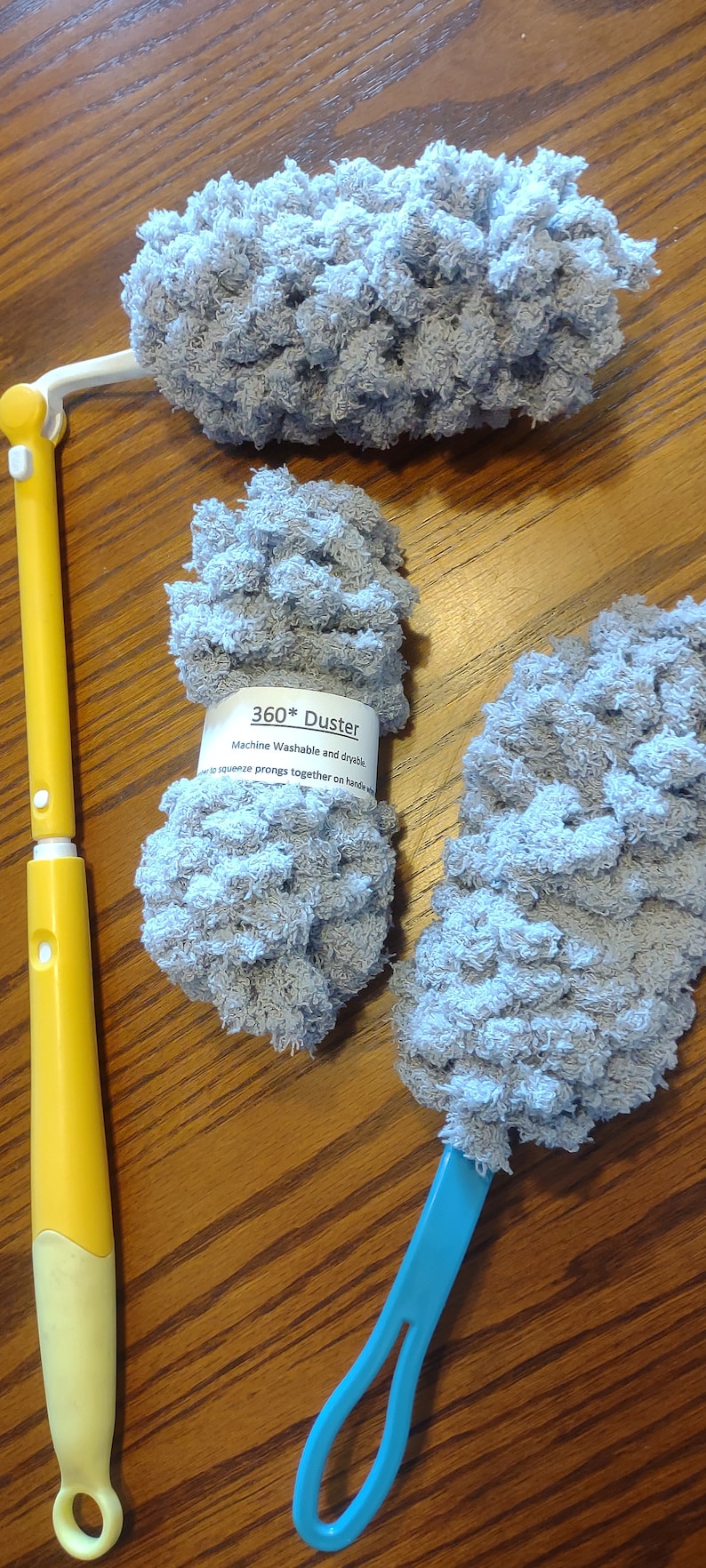 May include: Three gray microfiber dusters with yellow and blue handles. The dusters are labeled "360* Duster Machine Washable and dryable.  Squeeze prongs together on handle to use."