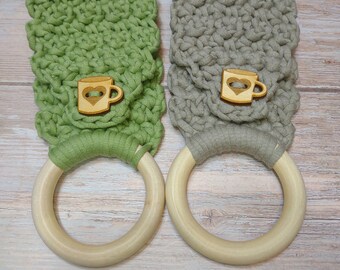 May include: Two crocheted dishcloths with wooden rings. One is green and the other is gray. Each dishcloth has a wooden cutout of a coffee mug with a heart on it.