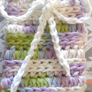 May include: A crocheted pouch with a white bow, made with a variety of colors including purple, green, and white.