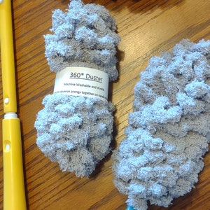 May include: Three gray microfiber dusters with blue and yellow handles. The dusters are machine washable and dryable. The label reads "360* Duster Machine Washable and dryable - to squeeze prongs together on handle w"