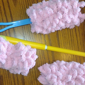 May include: Four pink fluffy dusters with handles. Two dusters have blue handles and two have yellow handles.