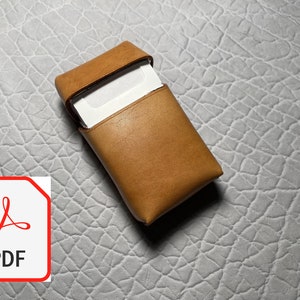 Può includere: Un astuccio in pelle marrone con un biglietto bianco all'interno. L'astuccio è aperto e il biglietto è visibile.
