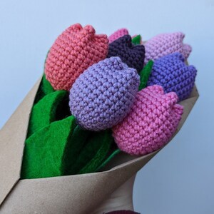 May include: A bouquet of crocheted tulips in shades of pink, purple, and brown, wrapped in brown paper with green felt leaves.