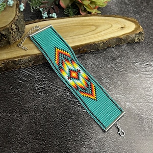 May include: A turquoise beaded bracelet with a geometric pattern in orange, yellow, and white. The bracelet has a silver clasp.