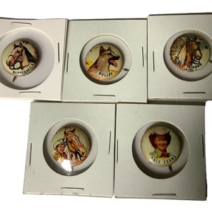 Peut inclure: Six boutons vintage avec des images de chevaux, d'un chien et d'une personne. Les boutons sont présentés dans des supports en carton blanc. Les boutons portent les inscriptions "Buttermilk", "Trigger", "Bullet", "Trigger", "Ringer" et "Dale Evans".