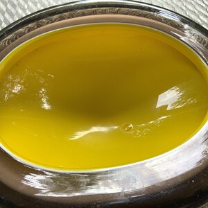 May include: A yellow glass bowl with a brown rim. The bowl is oval shaped and has a smooth, glossy finish.
