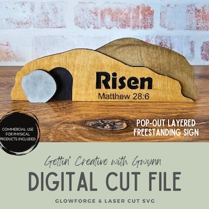 May include: A layered wooden sign with the word "Risen" and the text "Matthew 28:6". The sign has a pop-out design and is freestanding. The sign is made of light brown wood with a dark brown and gray accents.