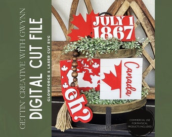 May include: A tiered wooden tray decorated with red and white Canadian themed decorations. The top tier has a sign that says "JULY 1 1867". The middle tier has a sign that says "Canada" and a red maple leaf. The bottom tier has a red and white sign with a maple leaf and the word "Girl" in red.