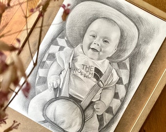 May include: A black and white pencil drawing of a baby wearing a hat and a shirt that says "The North Face".