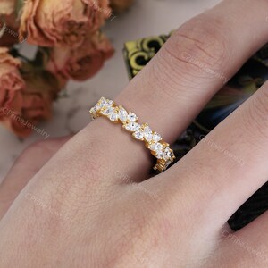 May include: A gold ring with a band of marquise-cut white gemstones. The ring is on a finger, with the brand name "CPFine Jewelry" visible in the background.