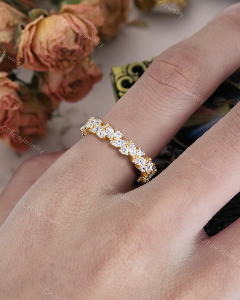 May include: A gold ring with a band of marquise-cut white gemstones. The ring is on a finger, with the brand name "CPFine Jewelry" visible in the background.