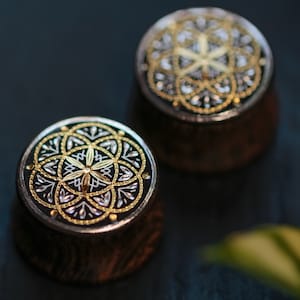 May include: Two wooden round ornaments with a black background and a silver and gold geometric design.