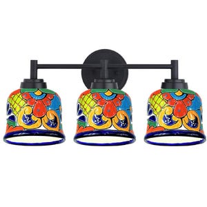 May include: A three-light vanity fixture with colorful, hand-painted ceramic shades. The shades feature a floral design in red, yellow, blue, and green. The fixture has a black metal frame and a round backplate.