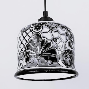 May include: Black and white ceramic pendant light with a floral design. The light fixture has a bell shape and a black cord.