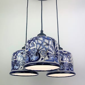 May include: A four-light pendant chandelier with blue and white ceramic shades featuring a floral pattern. The shades are suspended from a black metal canopy.