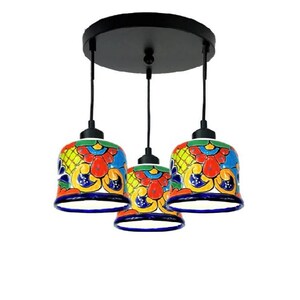 May include: A three-light pendant light fixture with colorful, hand-painted ceramic shades. The shades feature a traditional Mexican Talavera design with blue, red, yellow, and green colors.