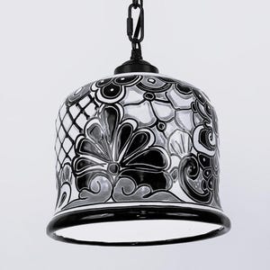 May include: Black and white ceramic pendant light with a floral pattern. The light has a black metal chain and a white ceramic shade.
