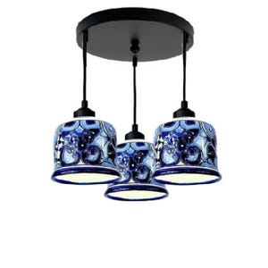 May include: A three-light pendant light fixture with blue and white ceramic shades. The shades have a floral pattern and are suspended from a black metal frame.