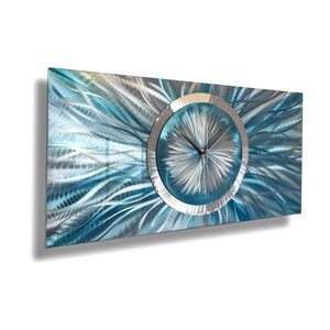 May include: A modern wall clock with a blue and silver metal design. The clock face is surrounded by a silver ring and has silver hands.