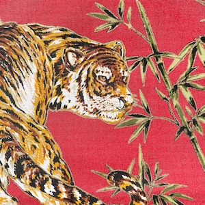 以下が含まれることがあります： 赤い布地に、虎と竹の葉のプリントが施されたクローズアップ。虎は画像の左側を向いており、縞模様が細かく描かれている。竹の葉は緑と黄色である。