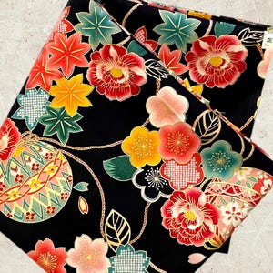 K&ouml;nnte beinhalten: Schwarzer Stoff mit einem sich wiederholenden Muster aus roten, rosa, gelben und gr&uuml;nen Blumen, Bl&auml;ttern und goldenen geometrischen Formen. Der Stoff hat ein traditionelles japanisches Design.