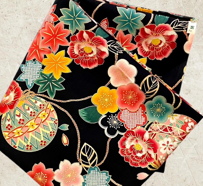 K&ouml;nnte beinhalten: Schwarzer Stoff mit einem sich wiederholenden Muster aus roten, rosa, gelben und gr&uuml;nen Blumen, Bl&auml;ttern und goldenen geometrischen Formen. Der Stoff hat ein traditionelles japanisches Design.