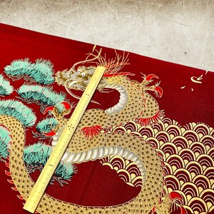 Puede incluir: Tela roja con un dise&ntilde;o de drag&oacute;n dorado y blanco. El drag&oacute;n est&aacute; enroscado alrededor de un pino y tiene escamas rojas y doradas. La tela tiene un patr&oacute;n repetitivo de olas.