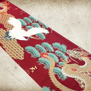 Puede incluir: Tela roja con un dise&ntilde;o de drag&oacute;n y gr&uacute;a dorado y blanco. El drag&oacute;n est&aacute; enroscado alrededor de un pino con hojas verdes. La gr&uacute;a est&aacute; volando sobre el &aacute;rbol. El fondo es una tela roja con un patr&oacute;n geom&eacute;trico dorado y blanco.