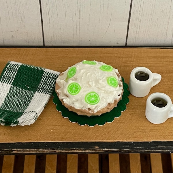 Four-Piece Keylime Pie set includes 1 pie on green doily, one green and white check towel and 2 cups of coffee in white mugs