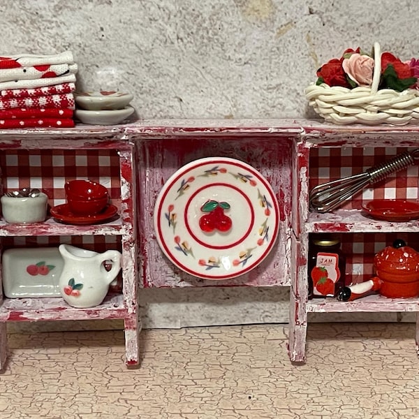Cherry themed upper wall cabinet crackled and distressed with shelves containing items of red and white and other accents