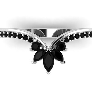 May include: A silver ring with a V-shaped band set with black marquise-shaped gemstones. The band is lined with smaller black round gemstones.