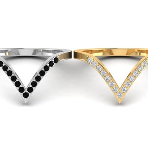 May include: Two V-shaped rings with a row of small black and white stones. The ring on the left is silver and the ring on the right is gold.