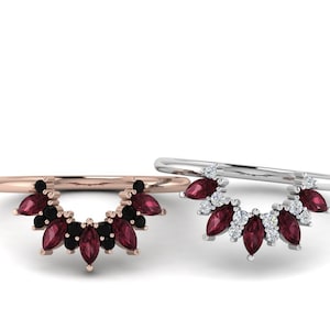 May include: Two delicate rings with a curved design featuring a row of marquise-shaped gemstones. The ring on the left has red gemstones and black accents, while the ring on the right has red gemstones and white accents.