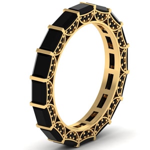 May include: A gold band ring with a row of black square-shaped gemstones set in a decorative design.
