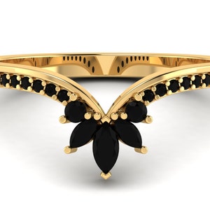 May include: A gold ring with a V-shaped band and black marquise-shaped stones set in the center. The band is lined with smaller black stones.