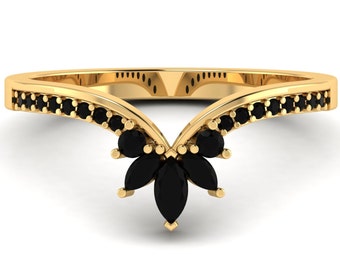 May include: A gold ring with a V-shaped band and black marquise-shaped stones set in the center. The band is lined with smaller black stones.