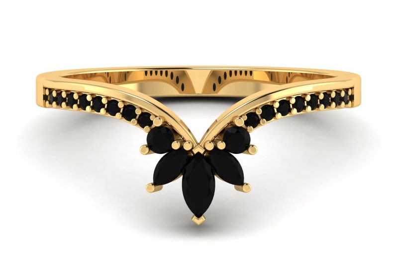 May include: A gold ring with a V-shaped band and black marquise-shaped stones set in the center. The band is lined with smaller black stones.