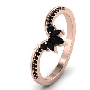 May include: A rose gold ring with a black marquise shaped gemstone cluster and black pave stones around the band.