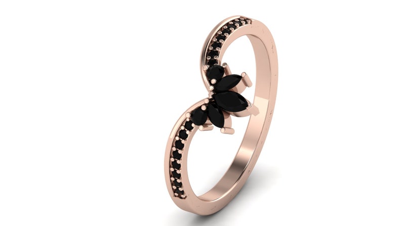 May include: A rose gold ring with a black marquise shaped gemstone cluster and black pave stones around the band.
