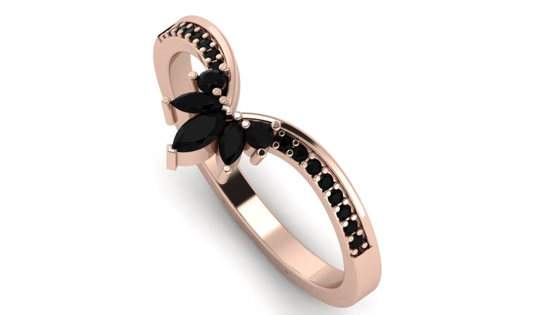 May include: A rose gold ring with a black marquise-shaped gemstone set in the center. The ring is accented with smaller black gemstones around the band.