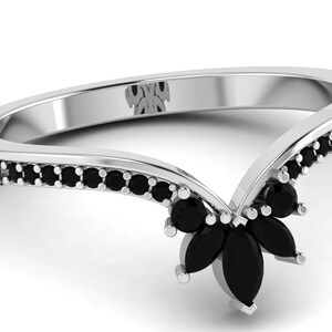 May include: A silver ring with a V-shaped band set with black marquise-shaped stones. The band is accented with smaller black round stones.
