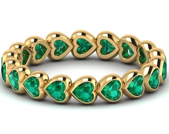 May include: A gold band ring with a row of emerald green heart-shaped gemstones.