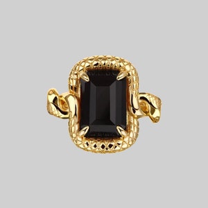 Peut inclure: Une bague en or avec une pierre précieuse noire sertie dans un motif de serpent.