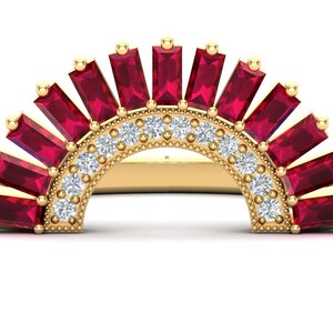 May include: A gold ring with a half-circle design featuring a row of small diamonds and a row of baguette-cut rubies.