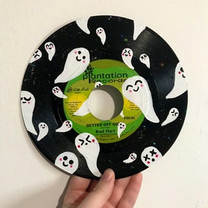 May include: A black vinyl record painted with white ghosts with pink cheeks and various facial expressions. The record label is green and white and says "Plantation Records" and "Better Off Gone" by Rod Hart.