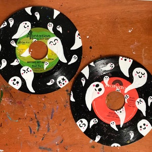 May include: Two black vinyl records painted with white ghosts. The records have labels with the text "Plantation Records" and "Polydor" and the titles "Better Off Go" and "Night Dreams".