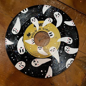 May include: A black vinyl record with a gold label that says "Golden Circle" and "KGC 228". The record is painted with white ghosts with red and black details. The ghosts have different expressions.