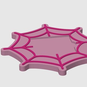 May include: A pink and magenta spiderweb-shaped object. The object has a raised border and a web design in a darker shade of pink. The design is a stylized representation of a spider's web.