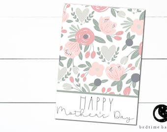 May include: A white card with a floral pattern in shades of pink and gray. The card has the text "Happy Mother's Day" printed on it.