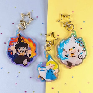 May include: Three colourful acrylic charms featuring cartoon characters. The first charm is a wizard with a pointed hat and a red and orange background. The second charm is a white character with a blue and white background. The third charm is a character with a blue and white dress and a pink and white background.
